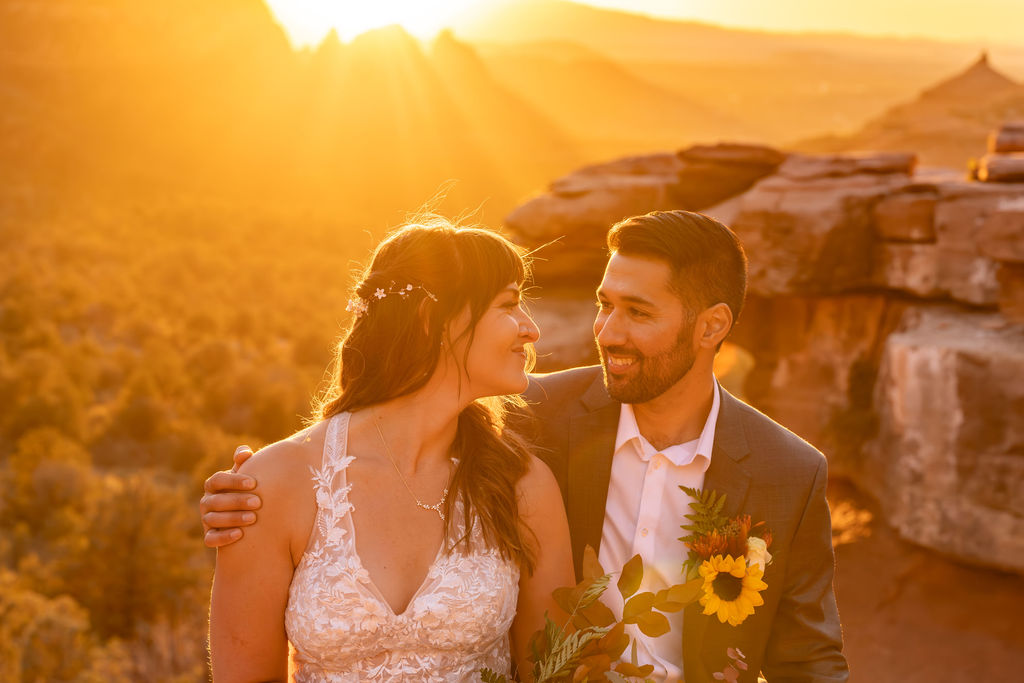 couple look at each other while sitting on rock during sunrise