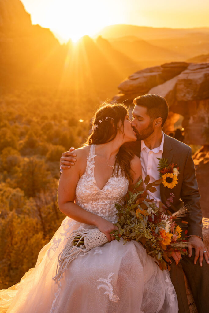 couple kiss while sitting on ledge during sunrise