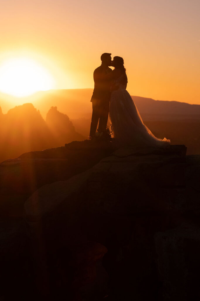couple kiss on ledge during sunrise