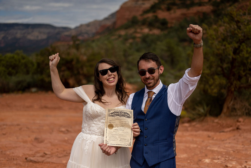 couple pose with wedding certificate after their sedona alternative wedding