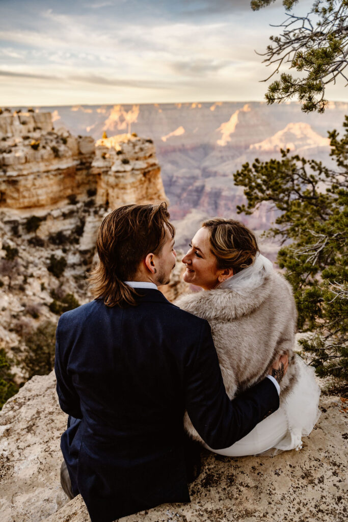 couple sits on overlook at Grand Canyon winter elopement