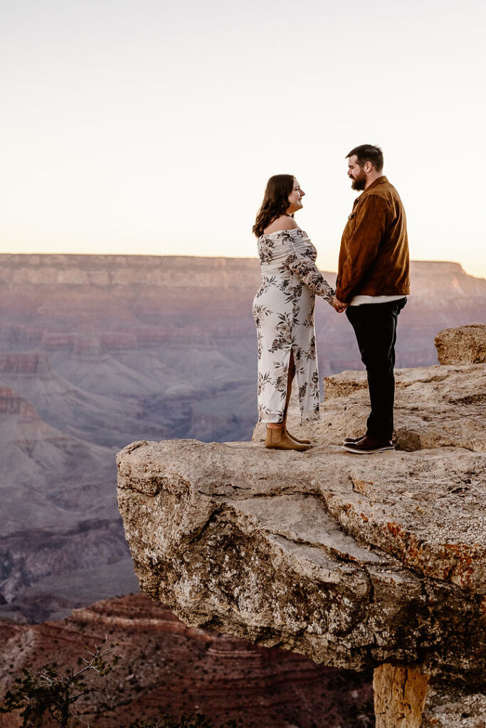 couple holds hands on overlook for winter engagement photos
