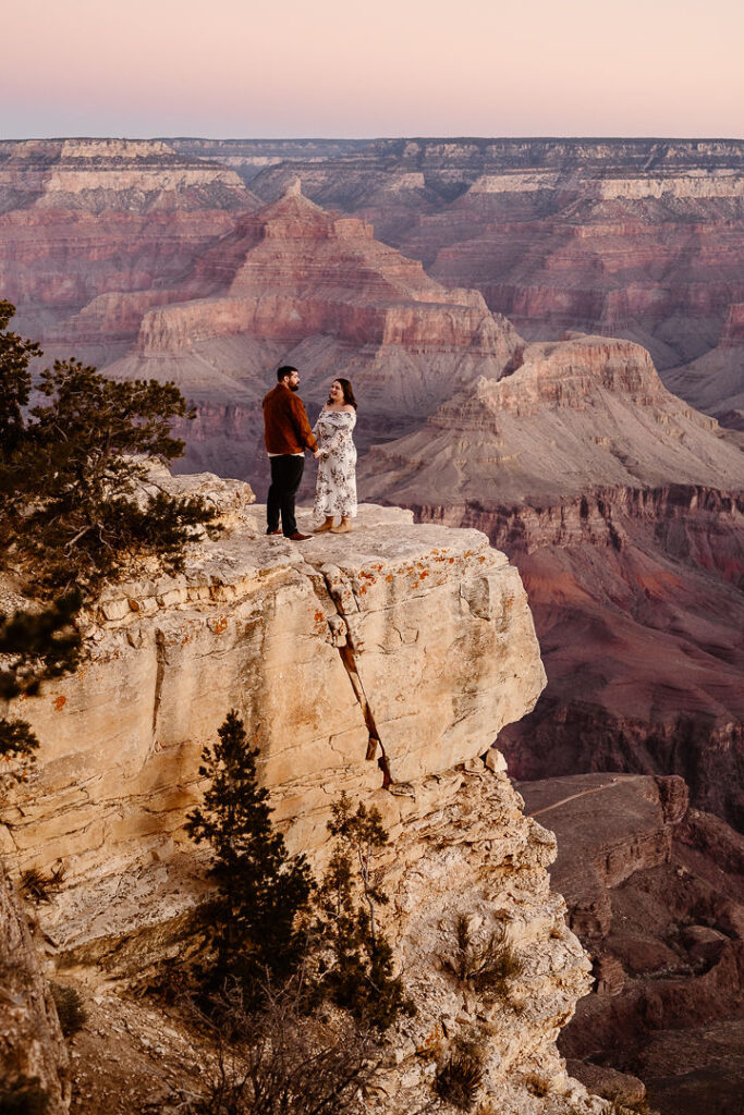 couple holds hands at overlook for winter engagement photos