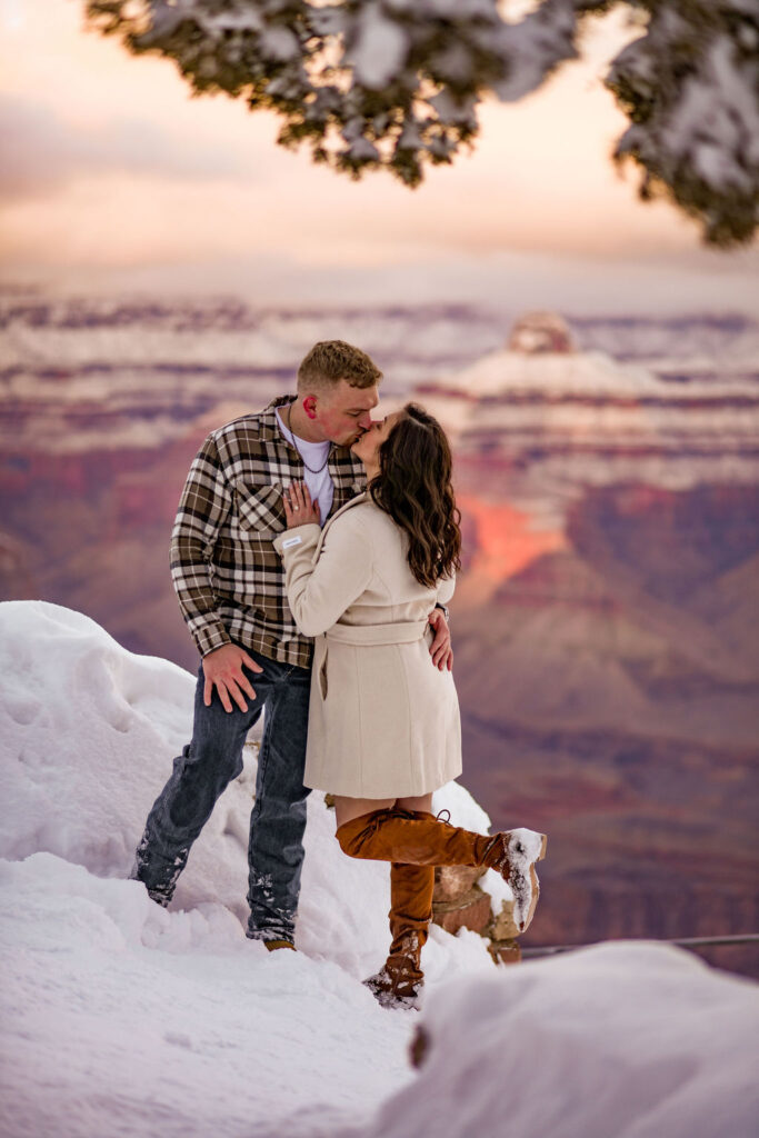 couple kisses in snow at sunset engagement session