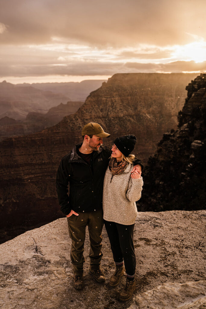 couple holds hands at snowy engagement session