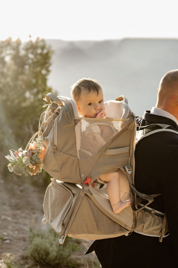 groom carrying daughter in backpack carrier during hike