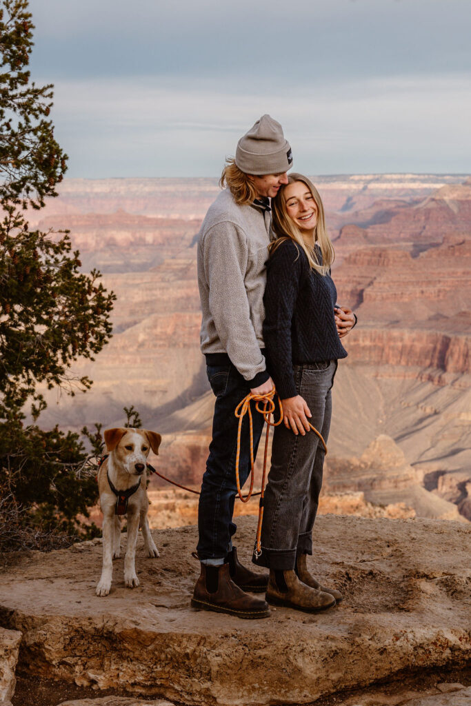 couple embraces with their dog during surprise proposal at the Grand Canyon