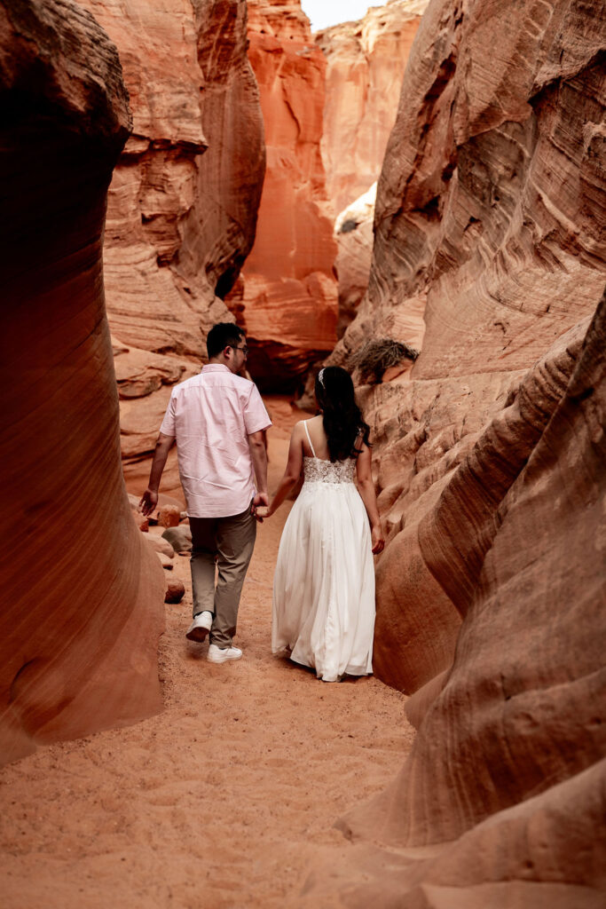 couple walks through red rock structures in Antelope Canyon