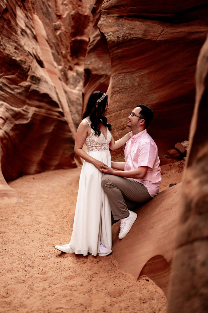 Couple poses along red rock structures in Antelope Canyon
