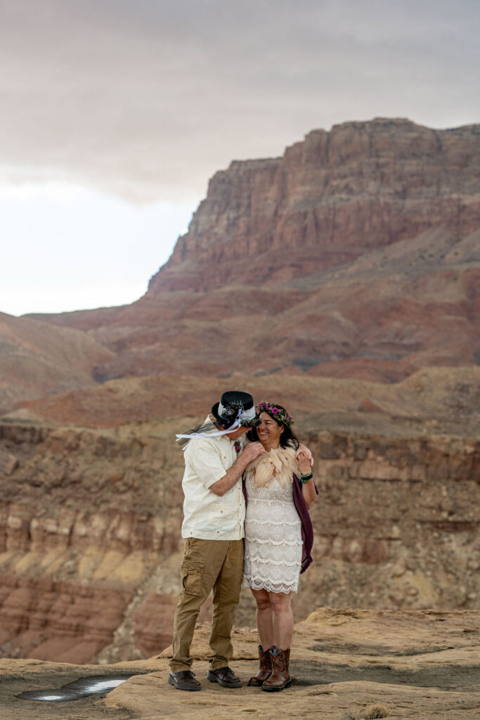 couple poses in front of large rock structure in Vermilion Cliffs Arizona