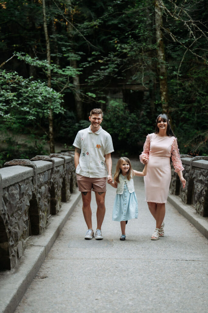 couple walk along path while holding hands with their daughter