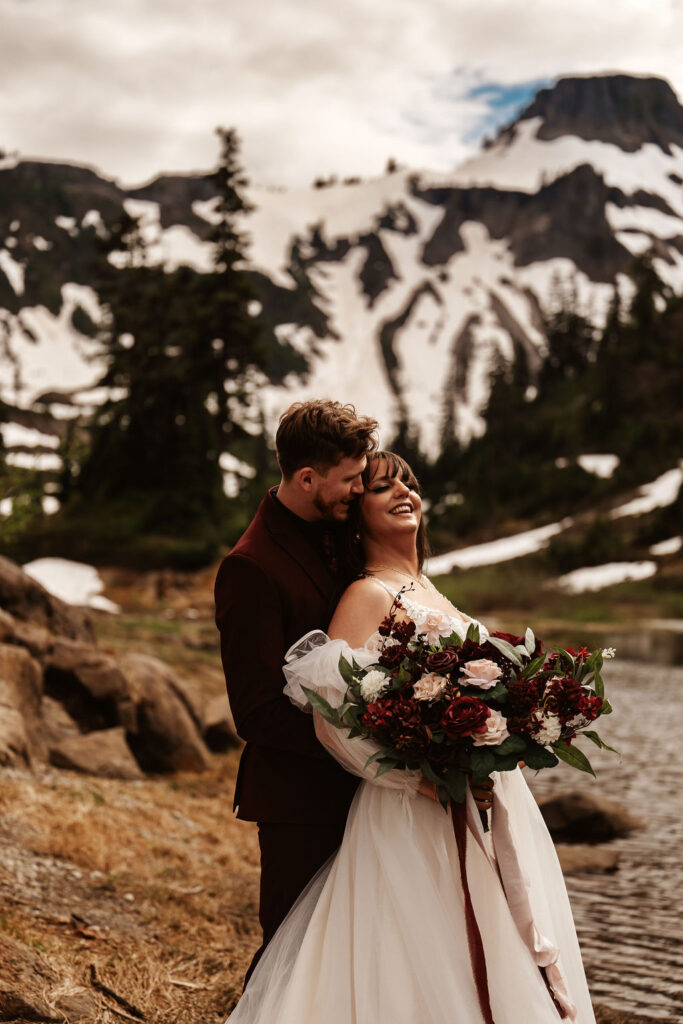 couple embrace in front of snowy mountain landscape