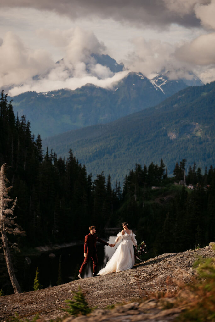 couple walk along path in front of mountain landscape