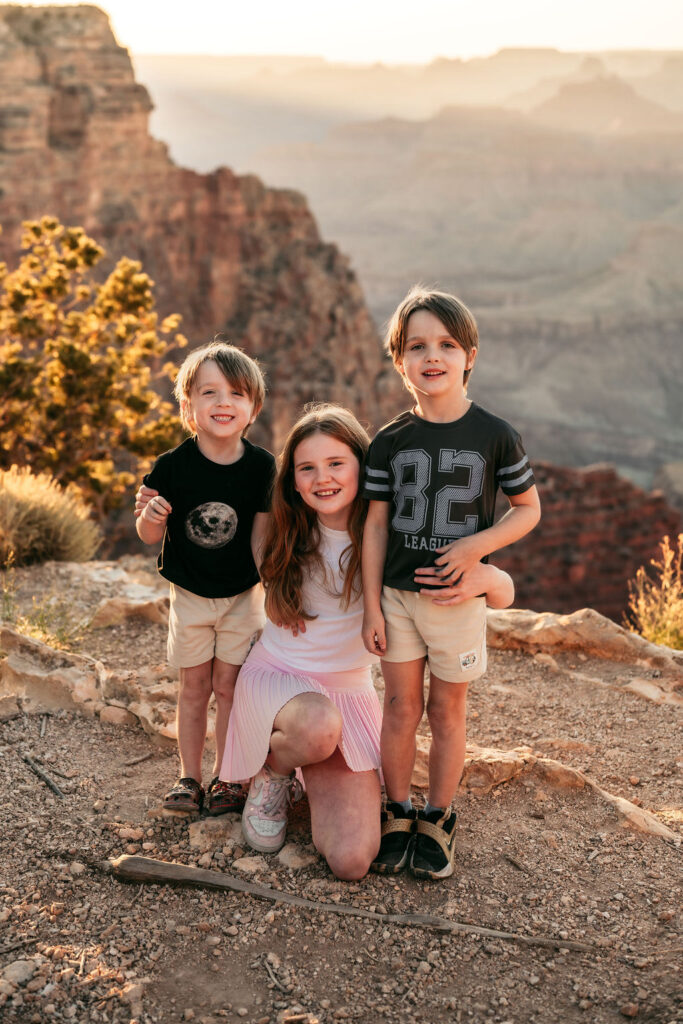 three kids posing together on rocky landscape of the Grand Canyon