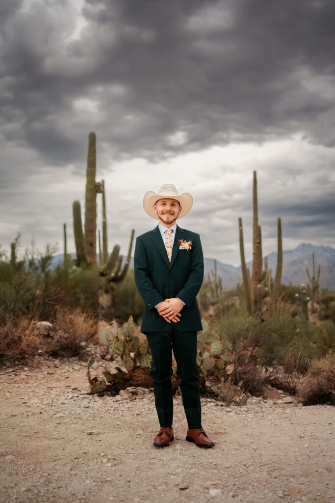 groom poses in front of desert landscape