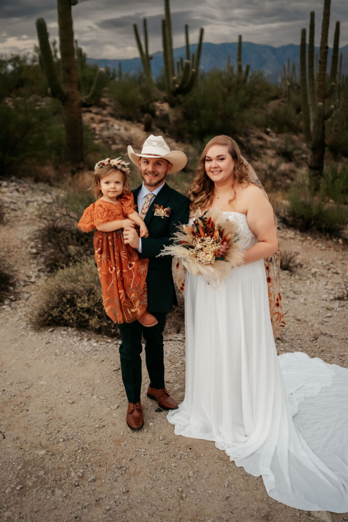 couple and daughter pose in front of cacti in Honey Bee Canyon Park
