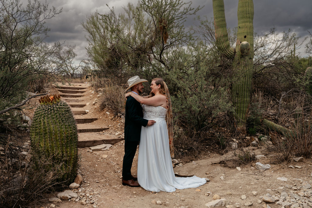 couple embrace in front of desert landscape in Honey Bee Canyon Park