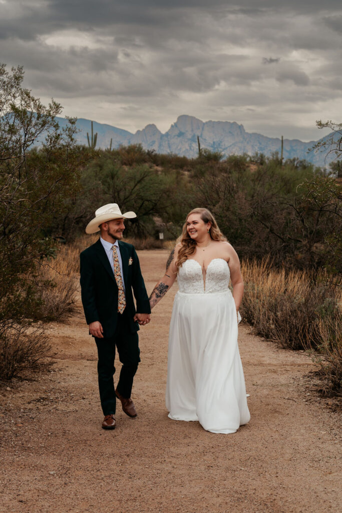 couple holds hands walking at desert elopement