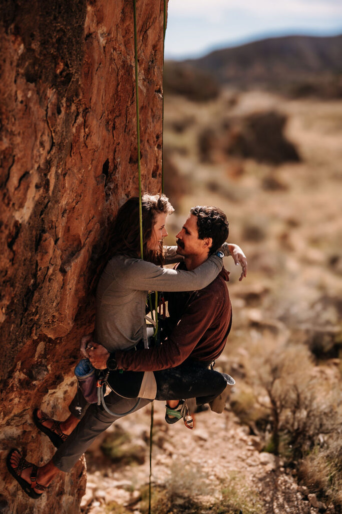 couple embrace during their rock climbing adventure engagement session