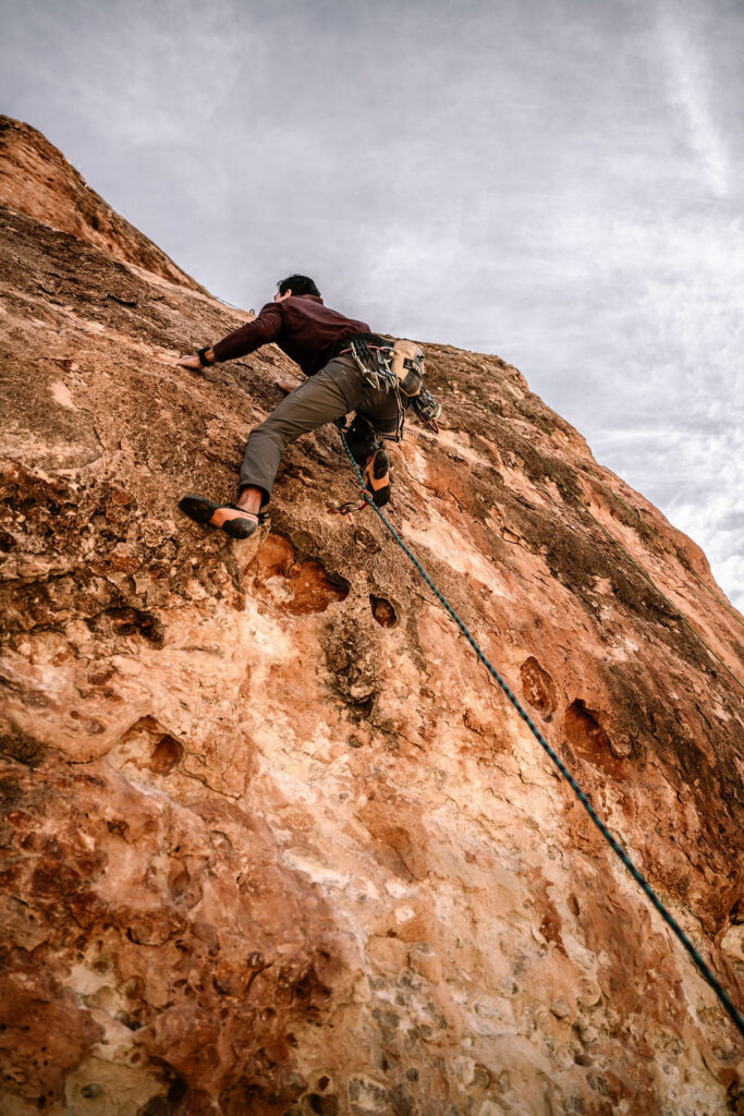man climbing up red rock