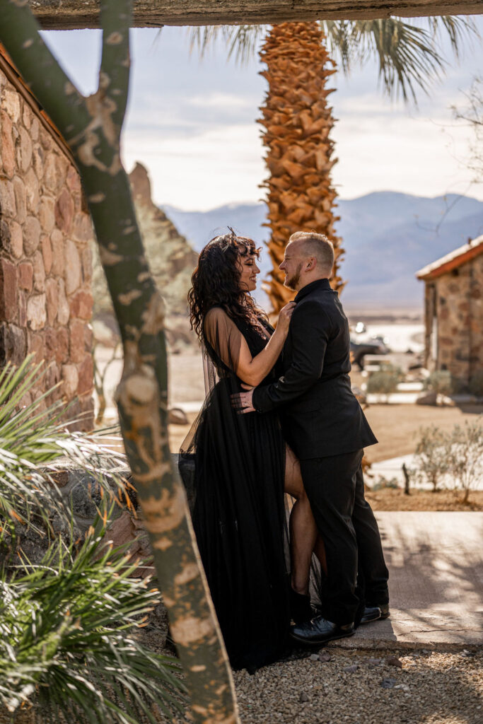 couple embrace while standing in front of palm tree