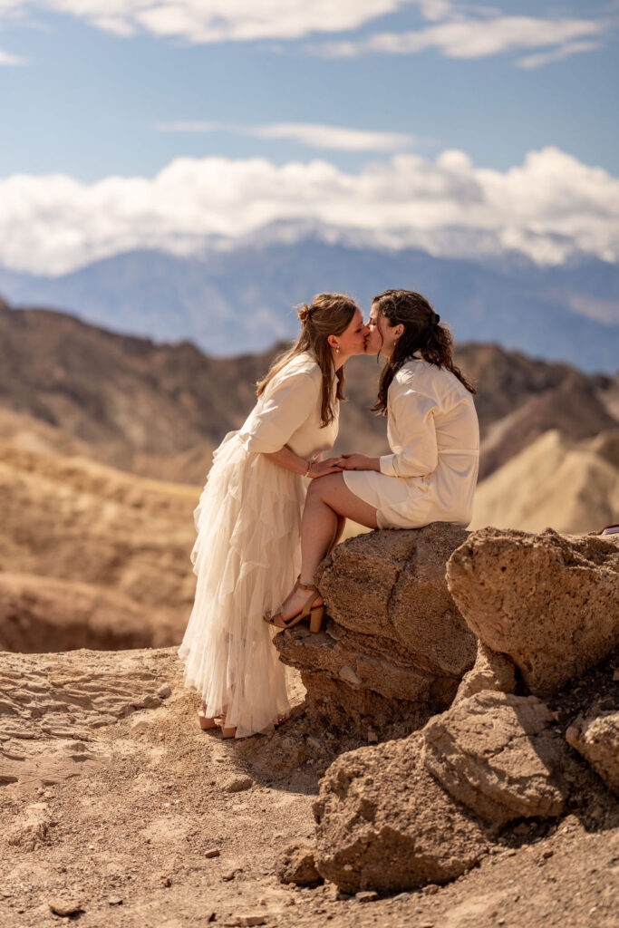 couple kissing while sitting on rock