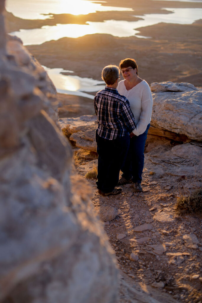 couple hold hands surrounded by rocks during sunrise shoot