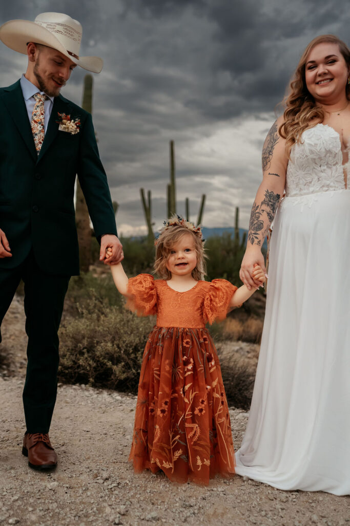 couple and their daughter holding hands during their western themed wedding