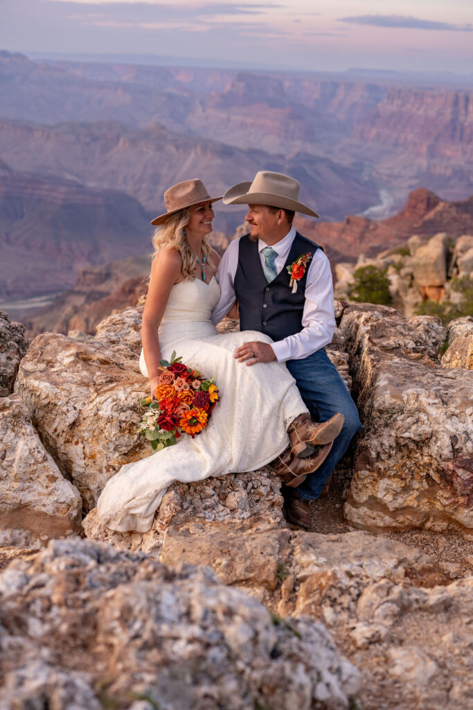 couple pose sitting on rock with the Grand Canyon in the background