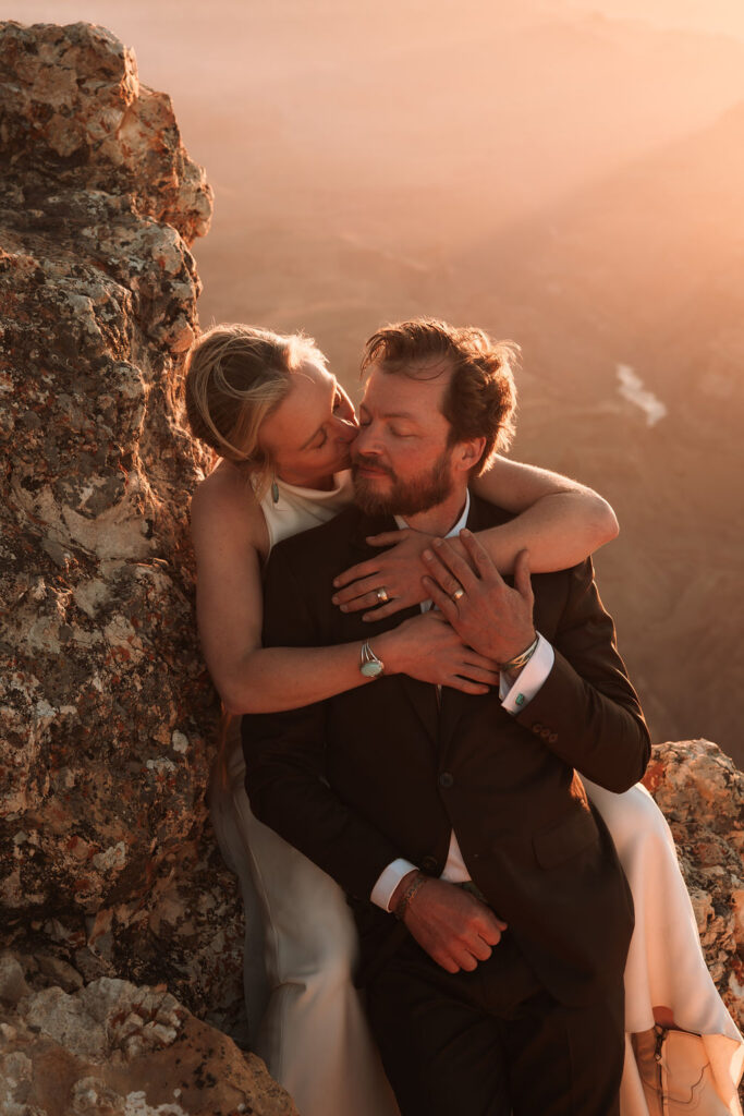 couple kiss while standing against rock