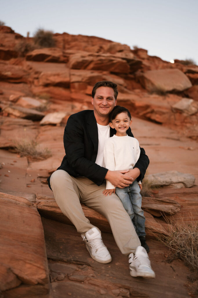 man and child pose on the desert rock