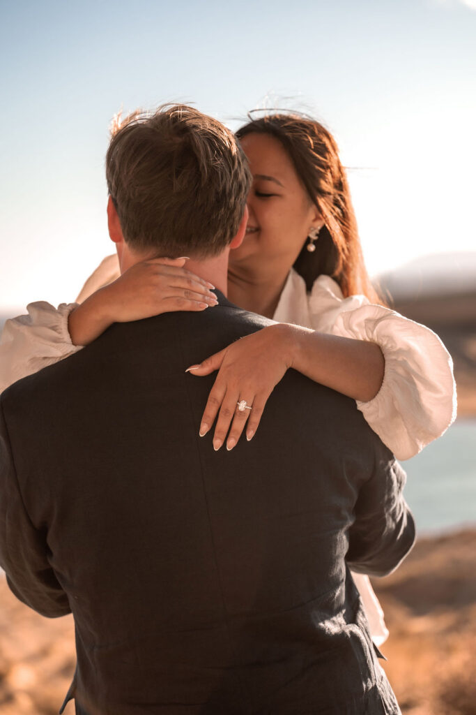 couple kiss and show off engagement ring