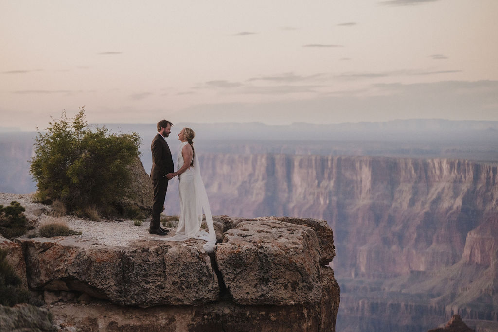 couple holding hands standing on edge at part of Grand Canyon adventure