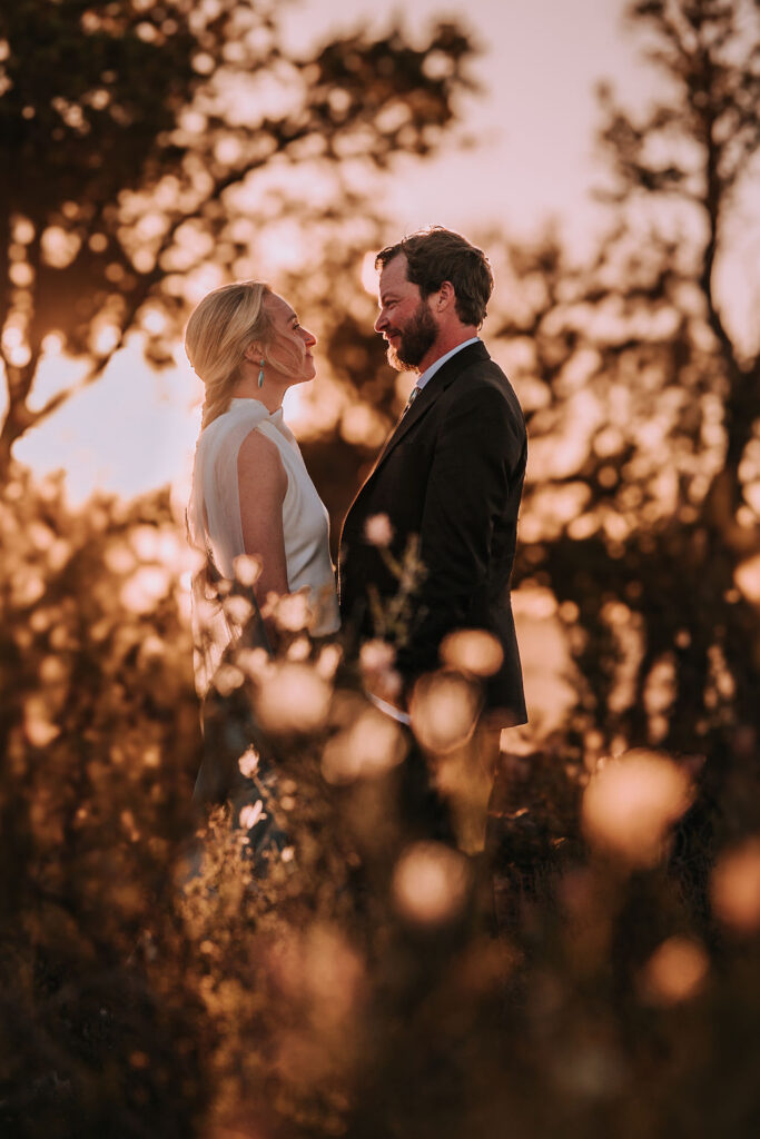 couple pose among the trees at sunset