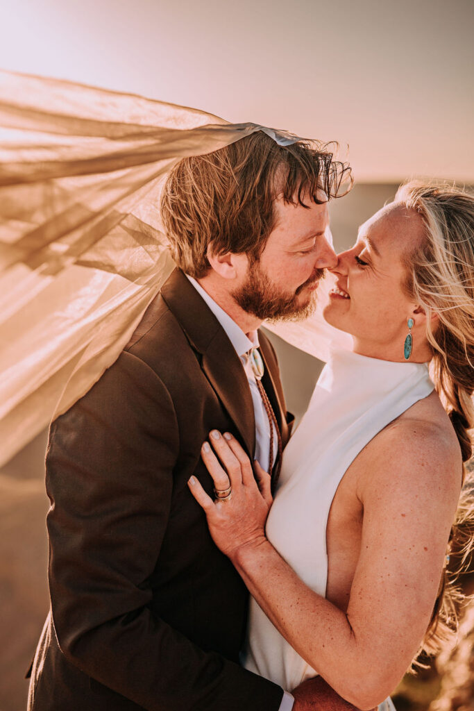 couple kiss at sunset under veil