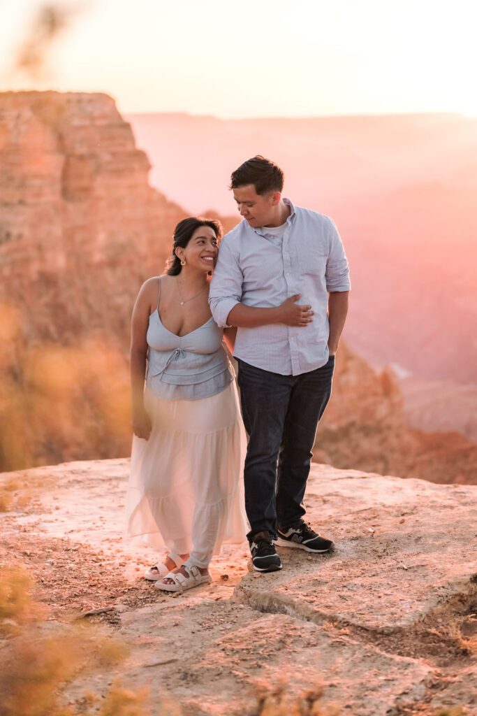couple embrace at sunset while standing on rocky ledge