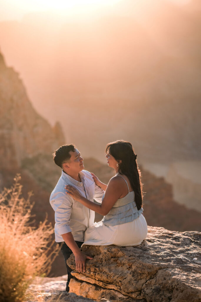 couple pose on rock during sunset at the Grand Canyon