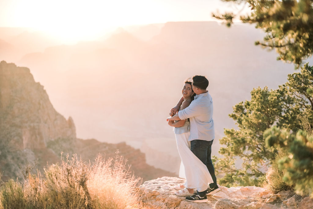 couple pose on rocky ledge at sunset