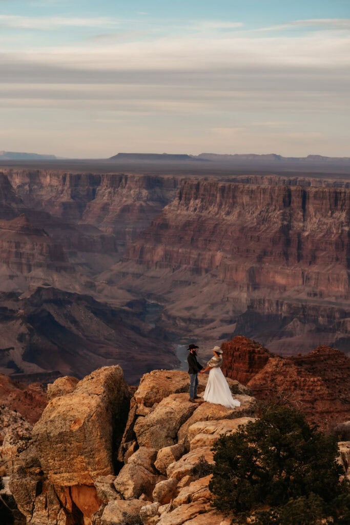 couple holds hands on cliff edge at Grand Canyon elopement