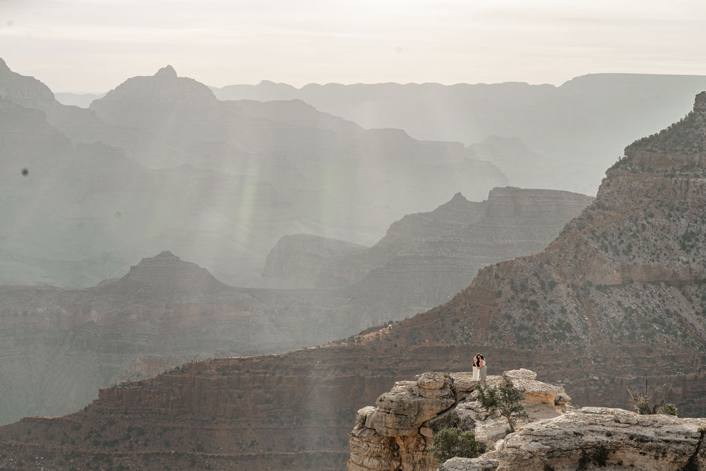 couple stands on overlook at Grand Canyon sunrise