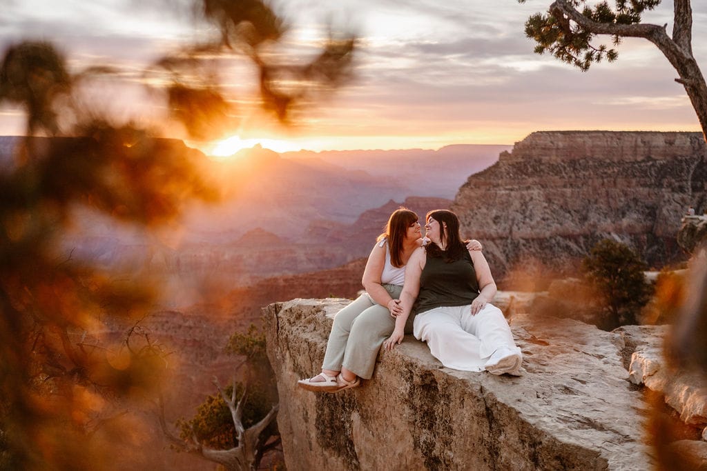 couple sits on Grand Canyon overlook at sunrise