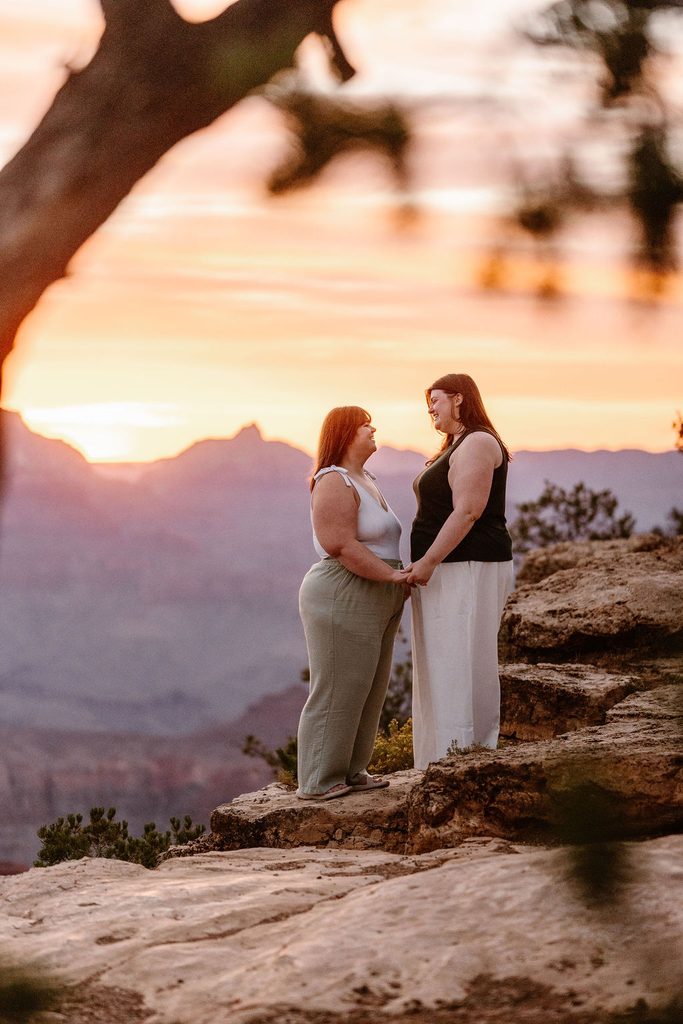 couple stands holding hands at sunrise