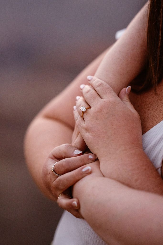 couple holds hands with engagement ring